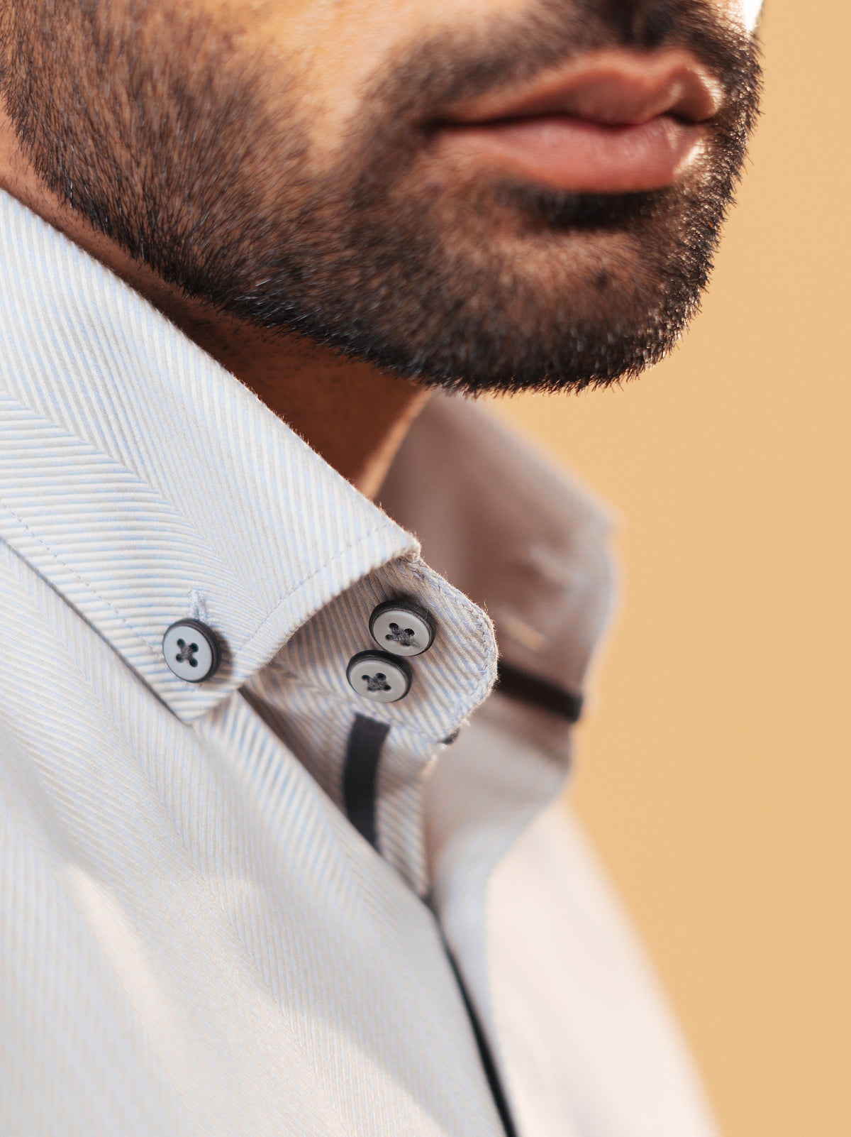 Half side collar view of ivory herringbone shirt on model